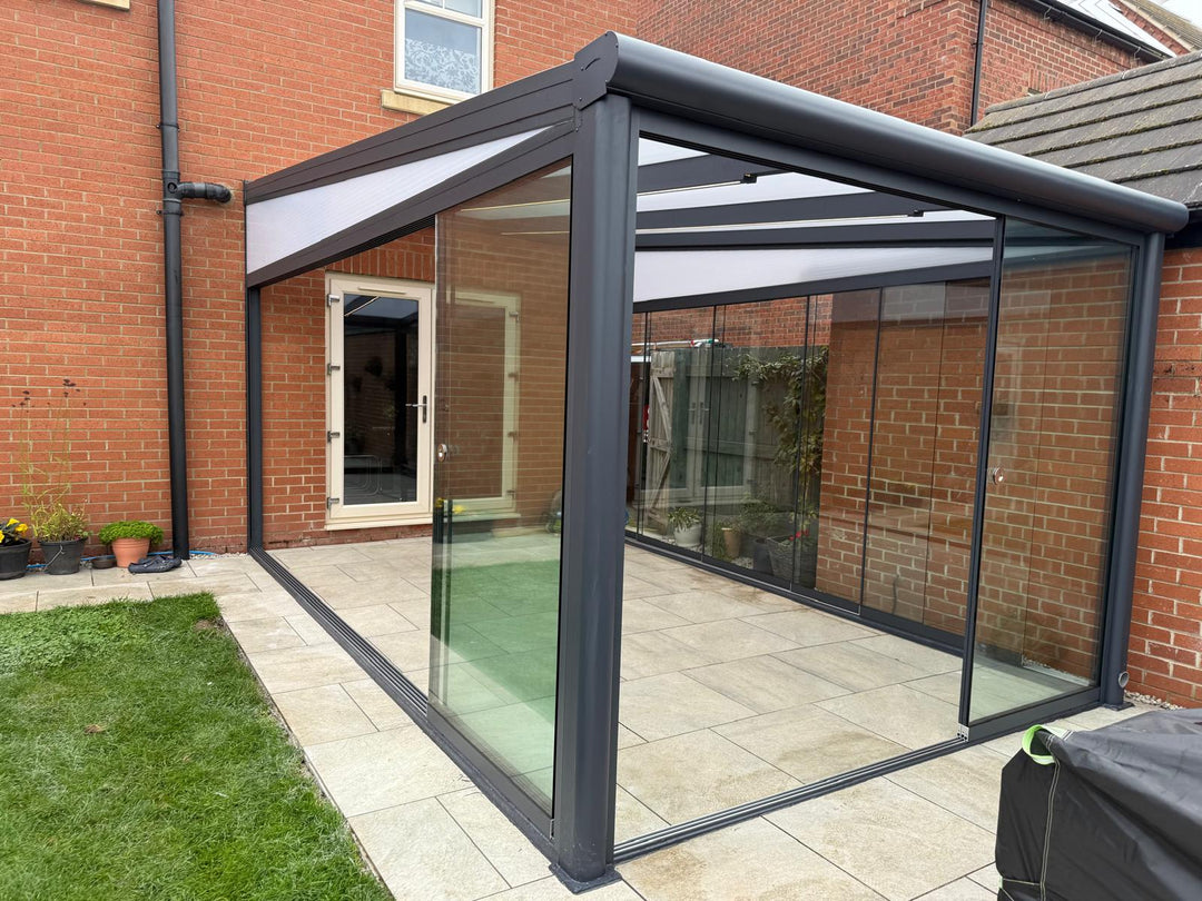 long 5M x 3M DePonti Bosco garden room against a brick wall and rear of a house. Installed by Midland Garden Furniture.