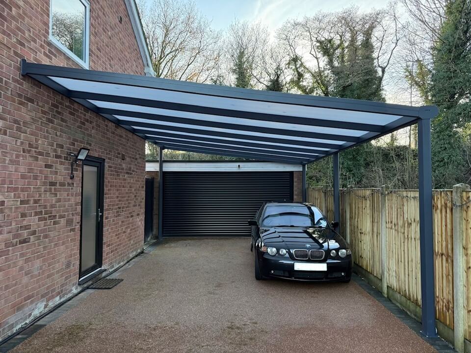 Car parked under a modern DePonti carport attached to a brick house. In front of double garage.