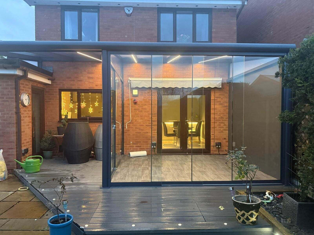 DePonti Vernada grey, with glazed room and open Vernada on grey decking on the back of modern house, with lighting at dusk.