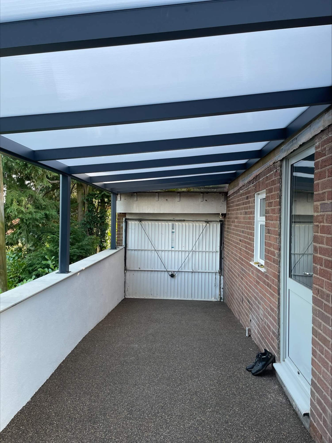DePonti Bosco Carport with dark grey frame and opal polycarbonate roofing.