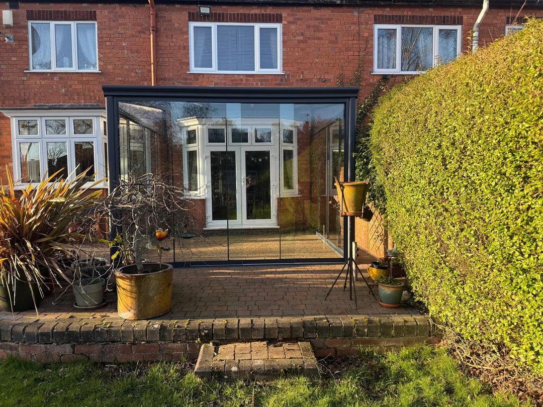 Bosco garden room 4M x 3M in grey with Fiano glazing floor to roof installed on brick paving at the back of a brick house.