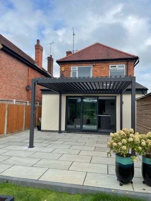 Chase Pergolas Nova Titan Perola Grey on light grey patio, against cream extension with doors opening into the Pergola.