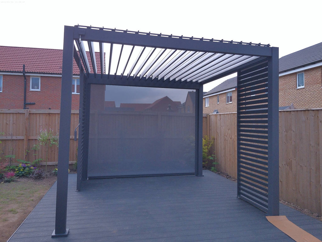 Grey Nova Titan pergola on grey decking in new build garden with wooden fence behind.