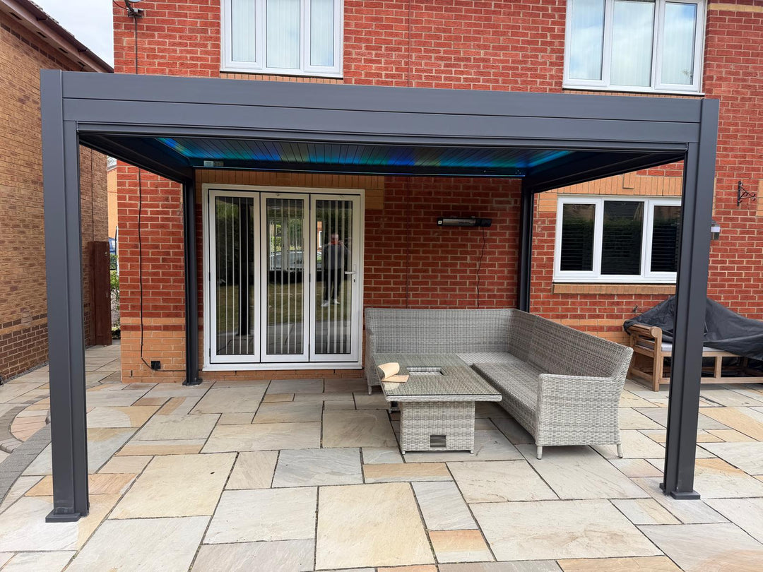 Nova Titan Pergola installation, Willingham, Cambridge, Cambridgeshire installed by Midland Garden Furniture. Inside Pergola image with privacy screen pulled down on patio area with a view of a modern brick house behind.