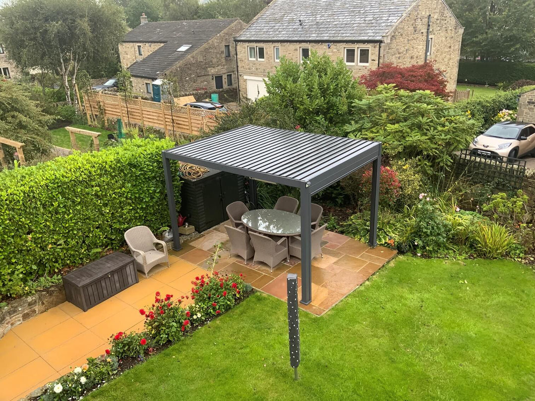 Nova Titan Pergola in back garden with bushes behind and 2 houses in the distance.