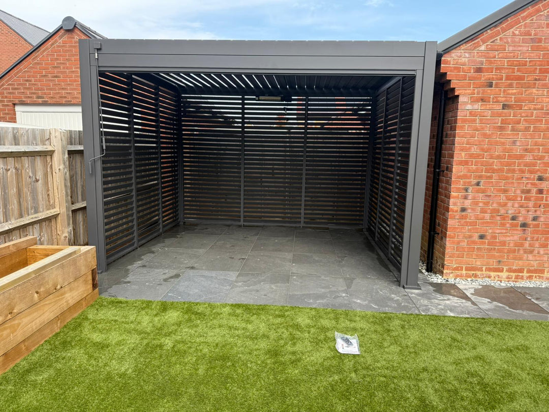 Grey Tian Pergola with fixed louvered grey walls, installed behind a new build garage and in-between fence.