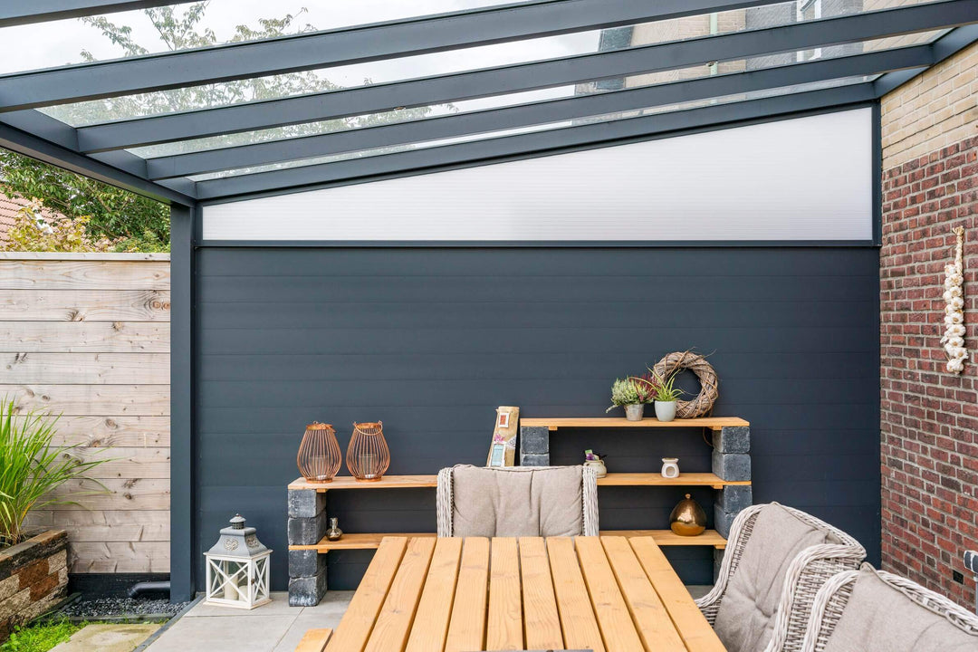 Outdoor patio area with wooden table, chairs, and shelves against a dark grey Grillo Fencing wall for privacy ideal for Bosco.