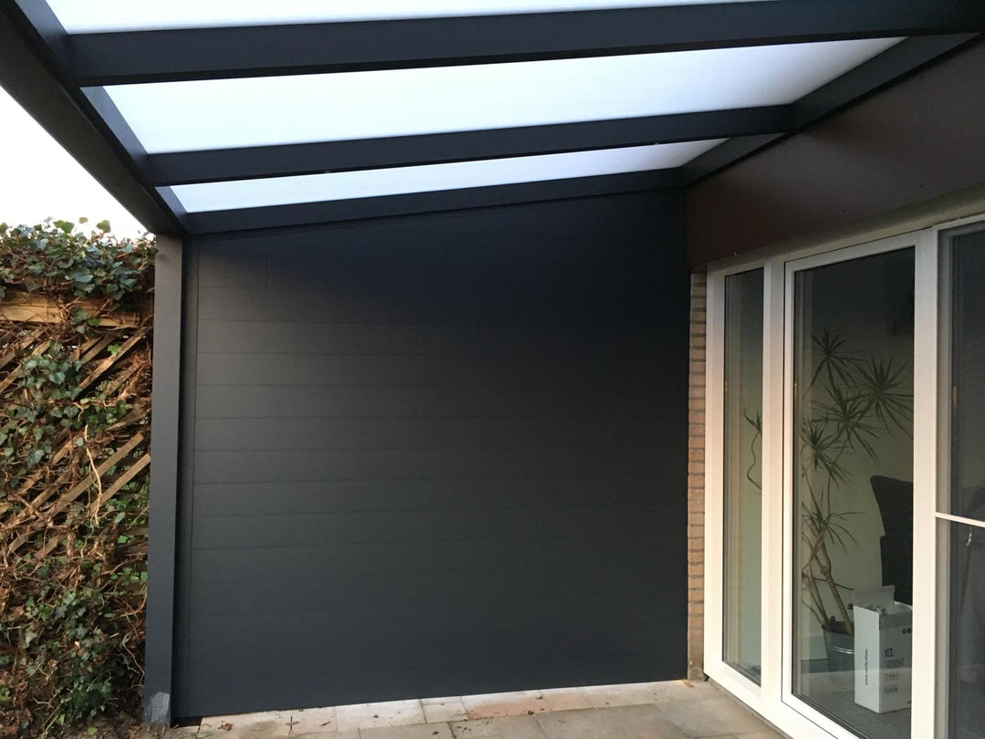 Modern outdoor patio with a retractable roof and sliding glass door. With dark grey solid Grillo wall system for privacy against neighbouring fence.