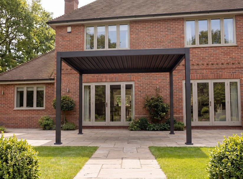 Hanover Signature Nova Titan Pergola IN front of modern large house with kept grass and bushes either side.