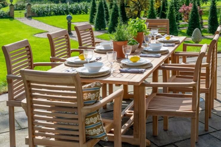 Hanover Teak Outdoor dining setup with wooden table and chairs on a patio