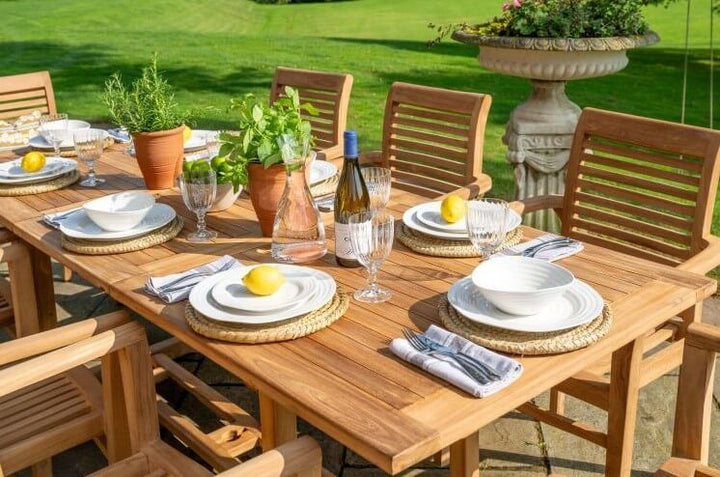 Hanover Teak  Outdoor dining setup with wooden table and chairs on a grassy lawn.