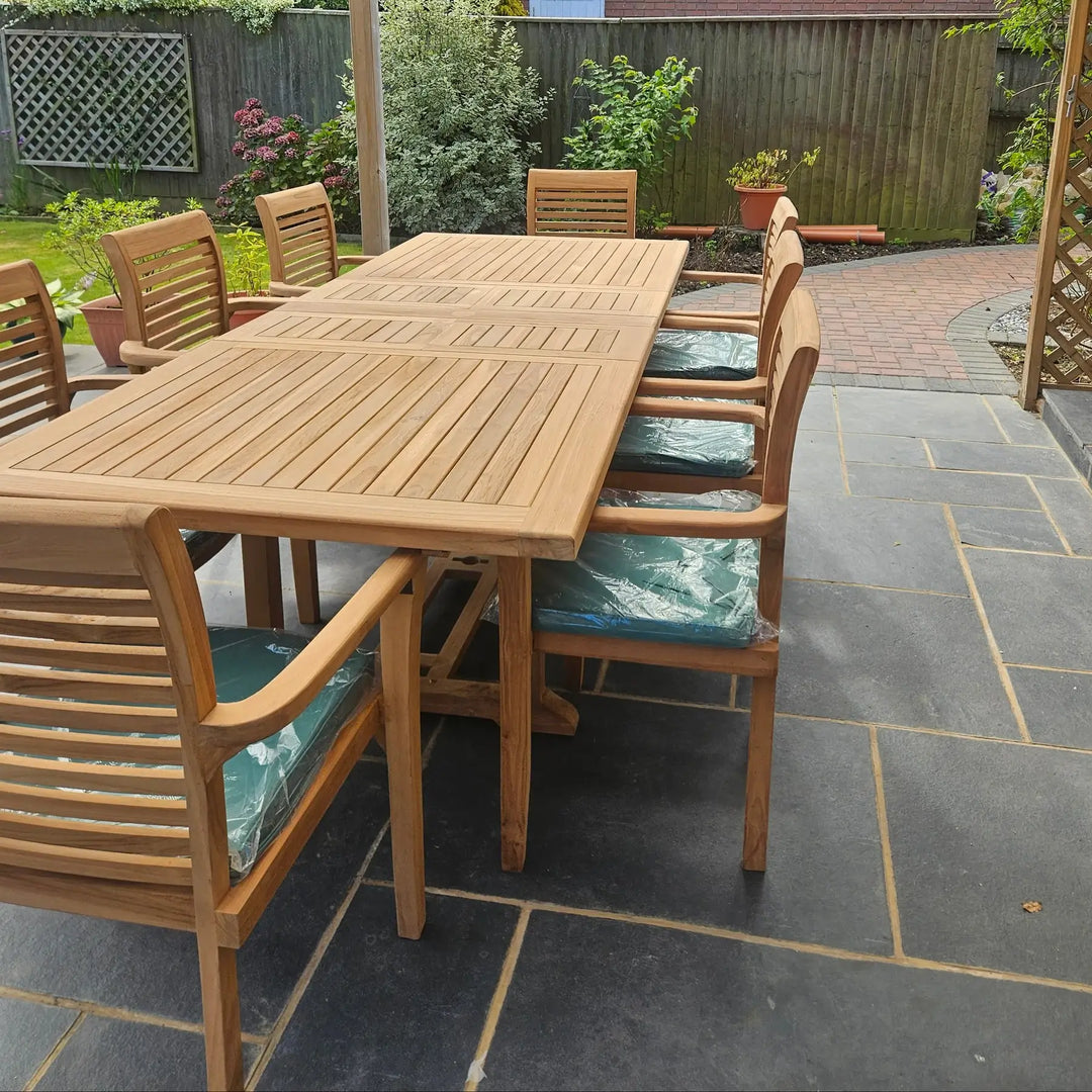Hanover Teak Wooden outdoor dining table with chairs on a stone patio