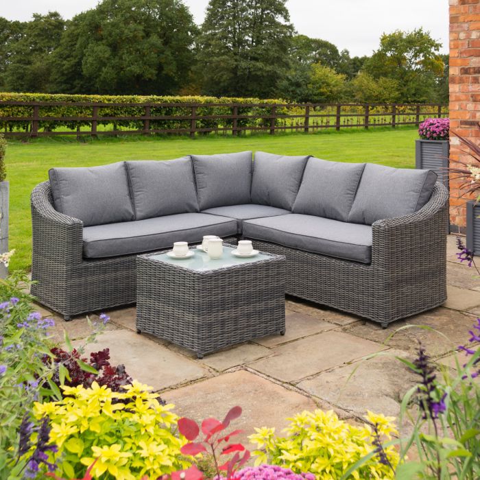 Bunbury Corner Garden Sofa Grey weave corner section in outdoor garden with hedge behind.