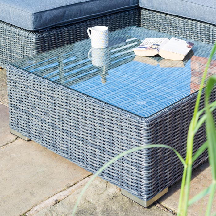 Heritage Vienna Rattan Corner Sofa side image with sofa and coffee table with fence behind and house wall. Close up coffee table.