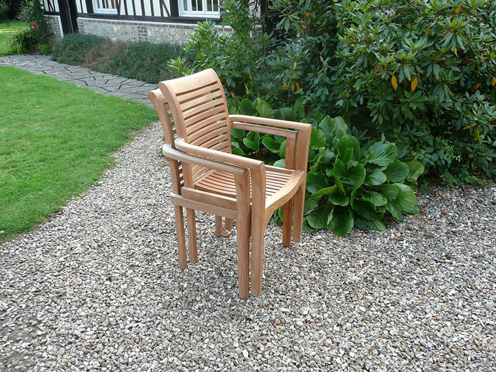 Two Teak wooden chairs on a gravel path with greenery in the background
