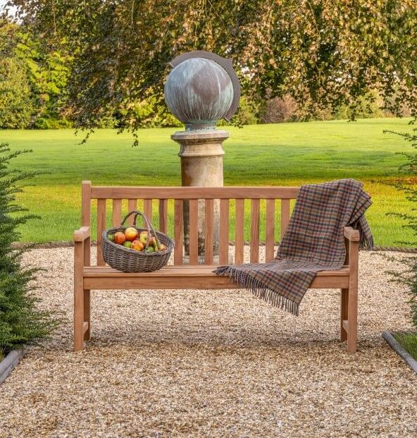 Hanover Teak Wooden bench with a basket of fruit and a plaid blanket in a garden setting