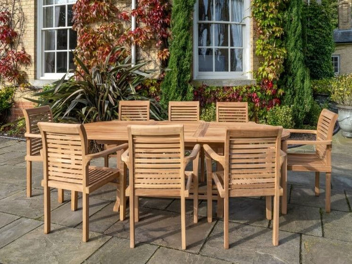 teak Wooden outdoor dining set on a stone patio with a garden and building in the background