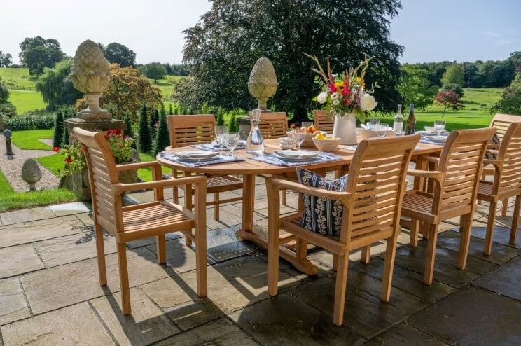 Teak outdoor dining setup with wooden furniture and a scenic garden view.