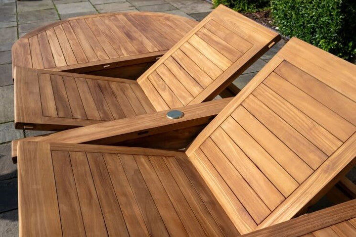 teak Wooden outdoor folding table on a stone surface with greenery in the background