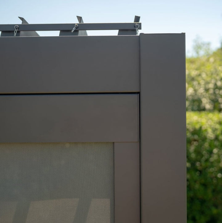 Close up corner image of Nova Titan Privacy Screen Grey 3M wide set inside a titan Pergola, with bushes in the back ground background, with privacy screen pulled slightly down. 