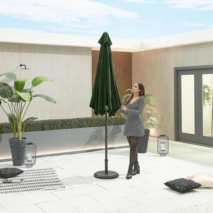 Woman setting up a green NOVA Outdoor living parasol on a patio with plants and lanterns.