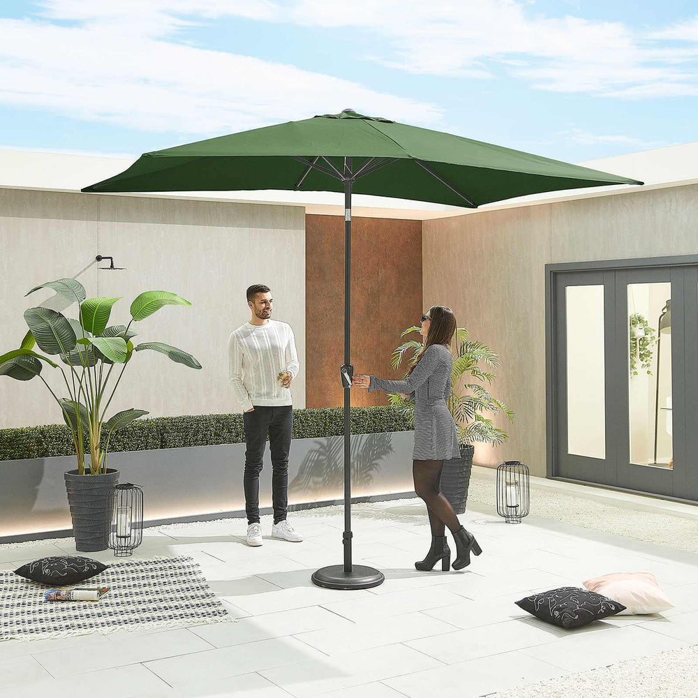 Two people interacting with a green Nova Outdoor Living Parasol on a modern patio.