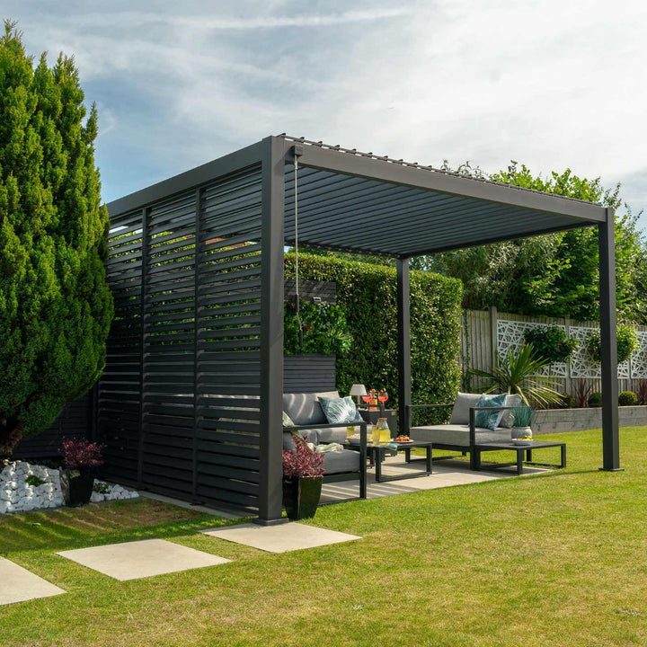 Grey Nova Titan Pergola in sunny garden with louvered walls to the left and modern grey sofa set