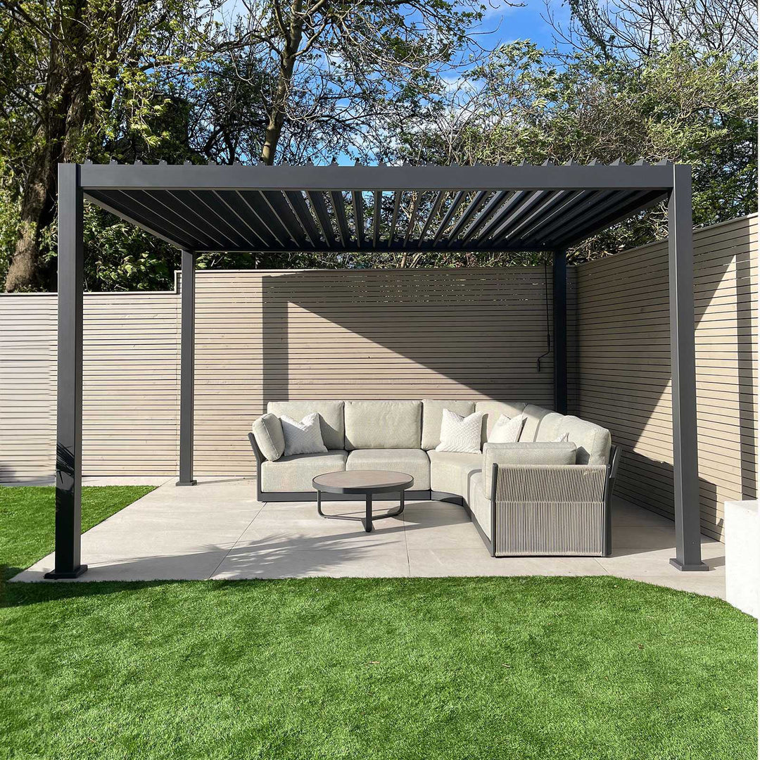 Nova Titan Pergola Grey 4M x 3M with louvers open on a white slabbed patio with beautiful light grey roped sofa and round coffee table in the middle.
