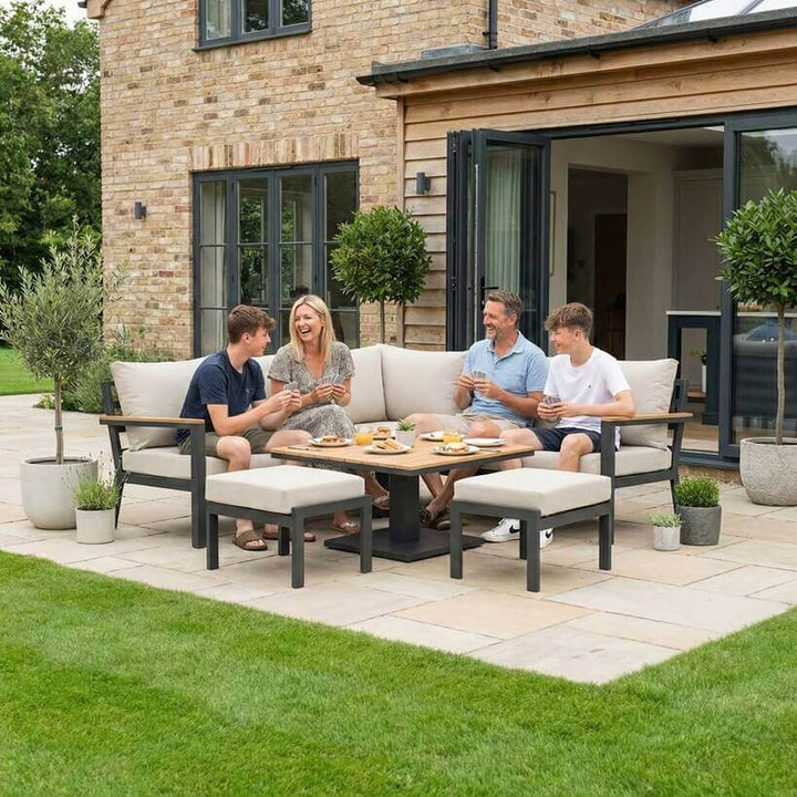 Nova Heidi outdoor living furniture set Midland Garden Furniture with people enjoying in front of a Cotswold house with plants at the back. corner sofa set. 