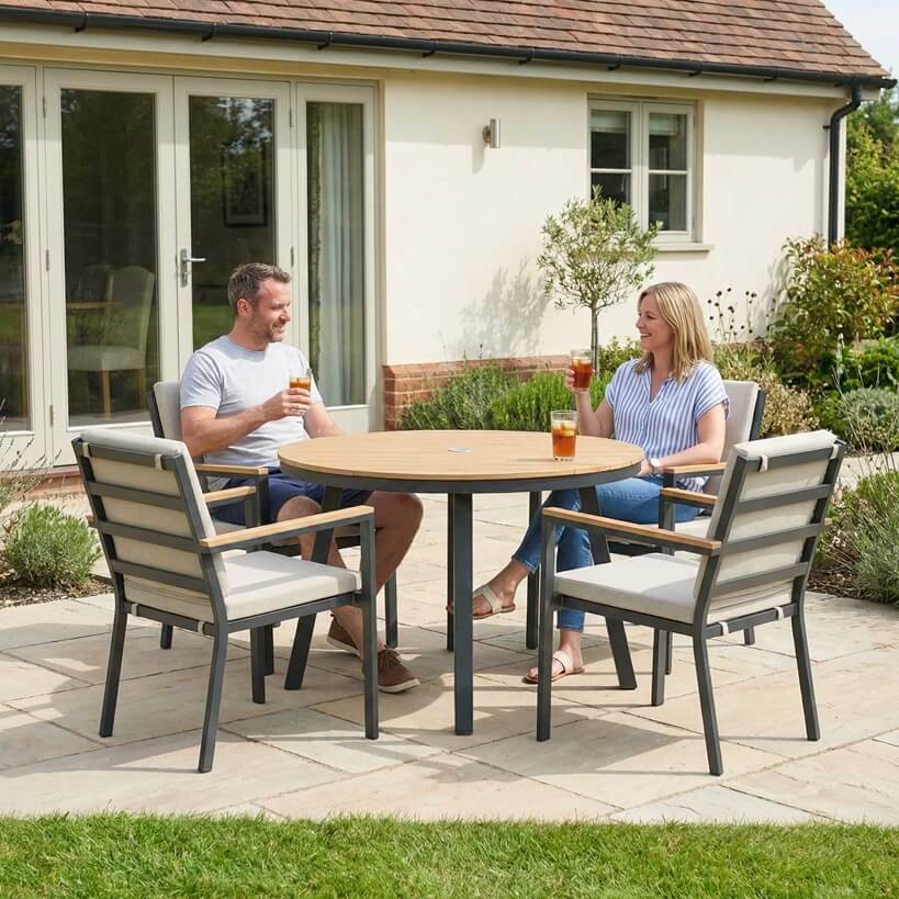 Nova Heidi outdoor living furniture set Midland Garden Furniture with people enjoying in front of a Cotswold house with plants at the back. 4 seater dining set round table