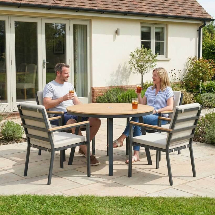 Nova Heidi outdoor living furniture set Midland Garden Furniture with people enjoying in front of a Cotswold house with plants at the back. 4 seater dining set round table