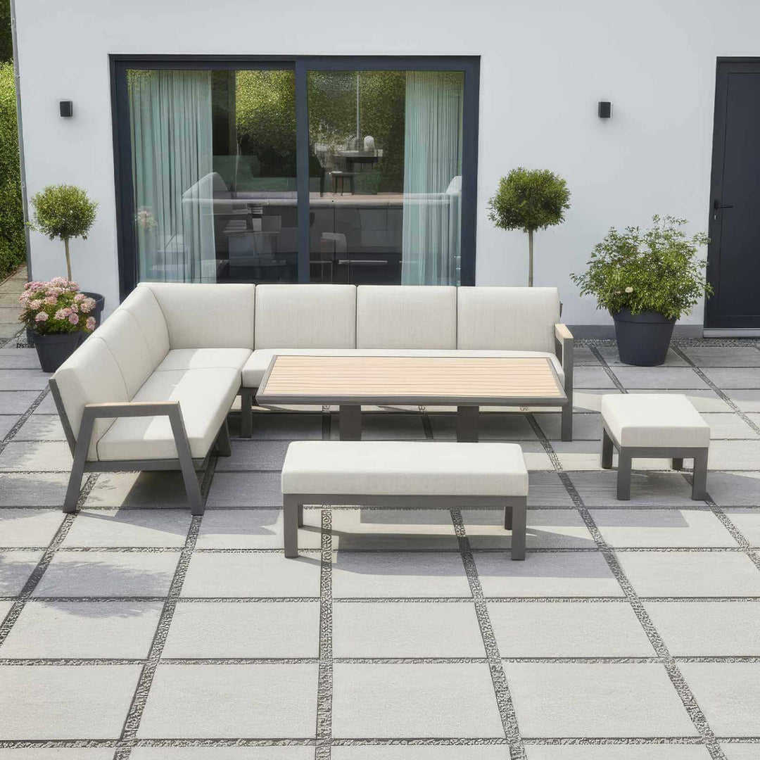 Nova Hunter outdoor living furniture set with a sectional sofa, rising table, and ottomans on a white background on a tiled patio.