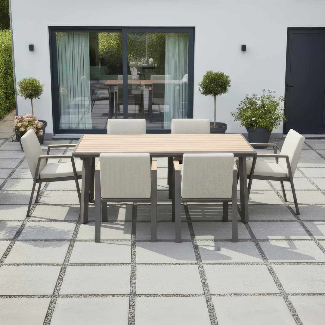 Nova hunter Outdoor patio dining set with table and 6 chairs on a tiled patio with modern white house behind and potted plants area.
