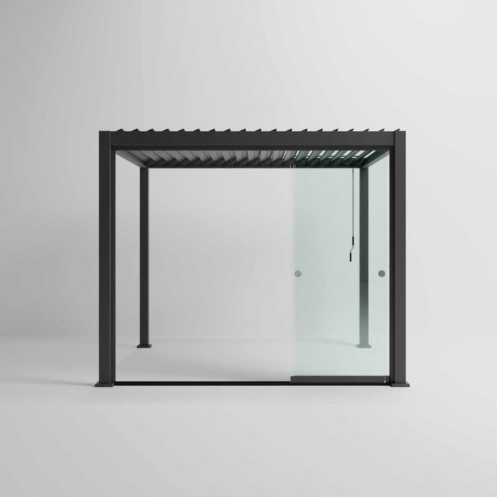 Nova Titan Pergola with glass sliding doors around the sides, with adjustable louvered roof. in anthracite grey with winder handle in pure white room. Front on shot angle.3M x 3M glass doors slid open.