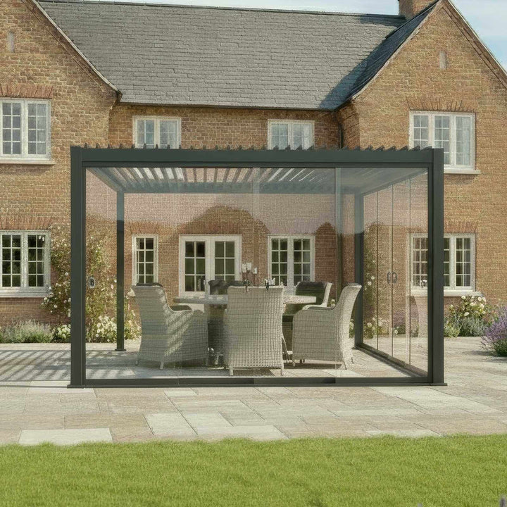 Nova Titan Pergola with glass doors in grey in front of a brick house cottage style. with grass to front on patio.