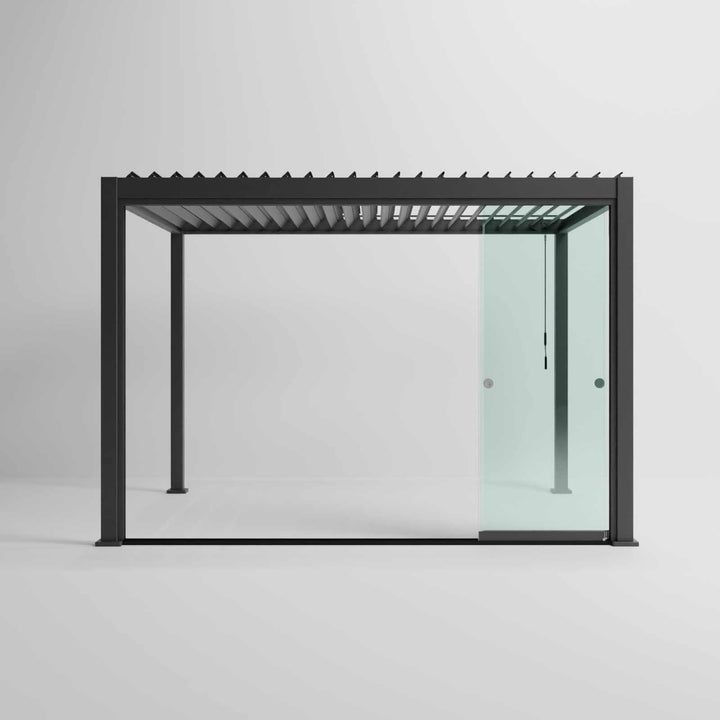 Nova Titan Pergola with glass sliding doors around the sides, with adjustable louvered roof. in anthracite grey with winder handle in pure white room. Front on shot angle. Glass doors slided all the way open.