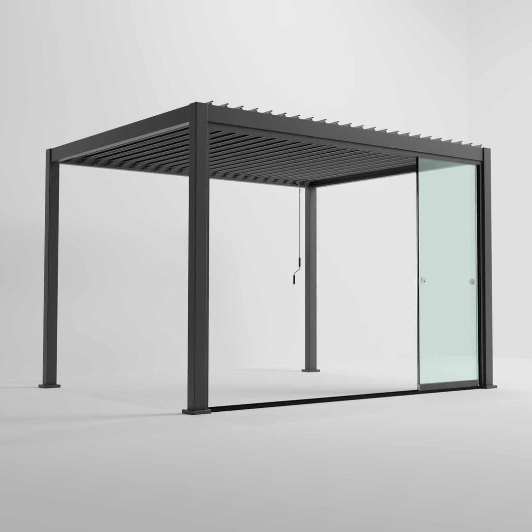 Nova Titan Pergola with glass sliding doors around the sides, with adjustable louvered roof. in anthracite grey with winder handle in pure white room. Image at a right angle with doors slid open. 4M x 3M pergola.