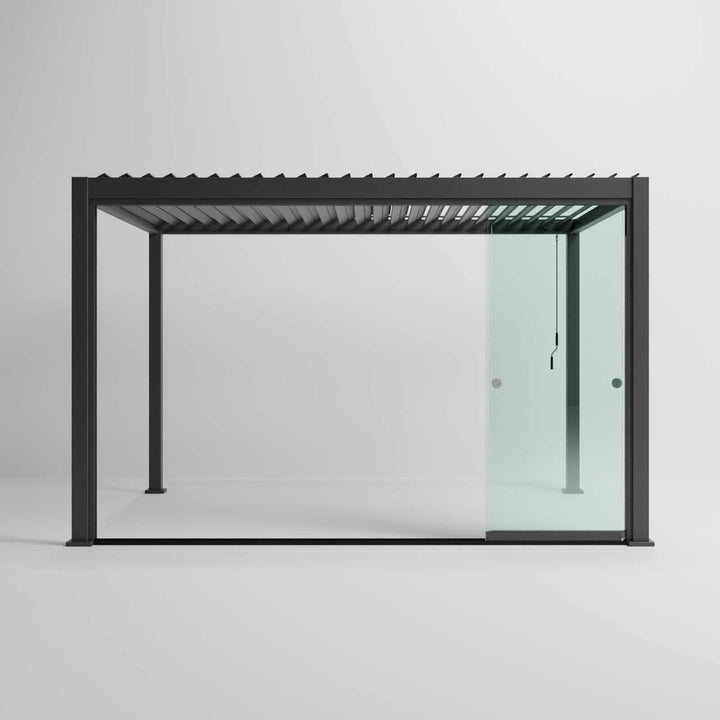 Nova Titan Pergola with glass sliding doors around the sides, with adjustable louvered roof. in anthracite grey with winder handle in pure white room. Front on shot angle. Glass doors sided open.