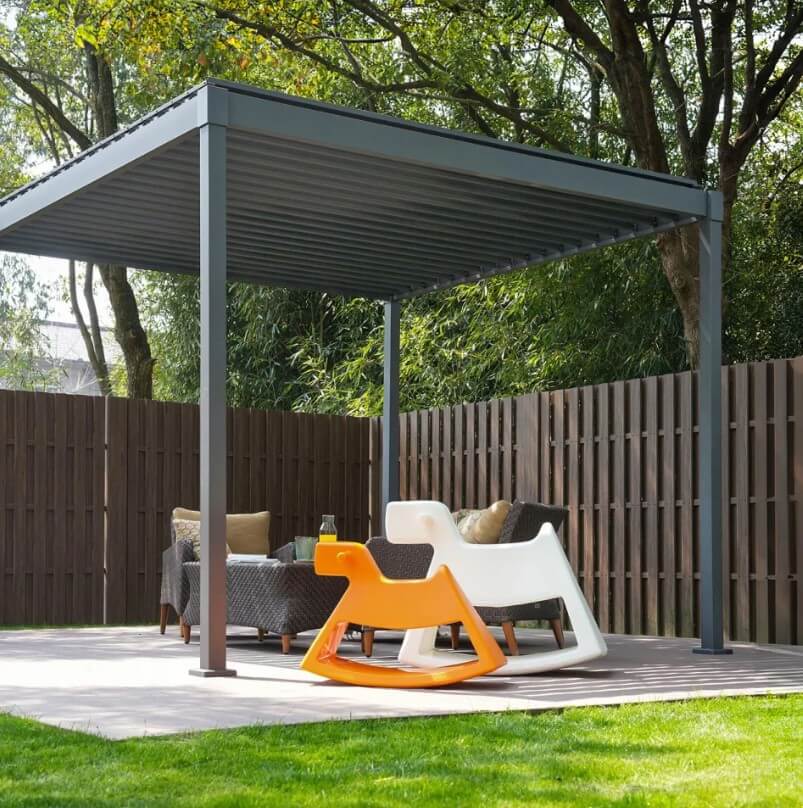 Outdoor patio with Nova Luna pergola, chairs, and a rocking chair on a grassy area.