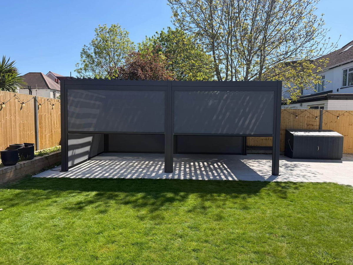 Nova Titan Aluminium Pergola installed in Redhill, Surry by Midland Garden Furniture on new patio slabs with grass to from and tress behind on bright sunny morning.