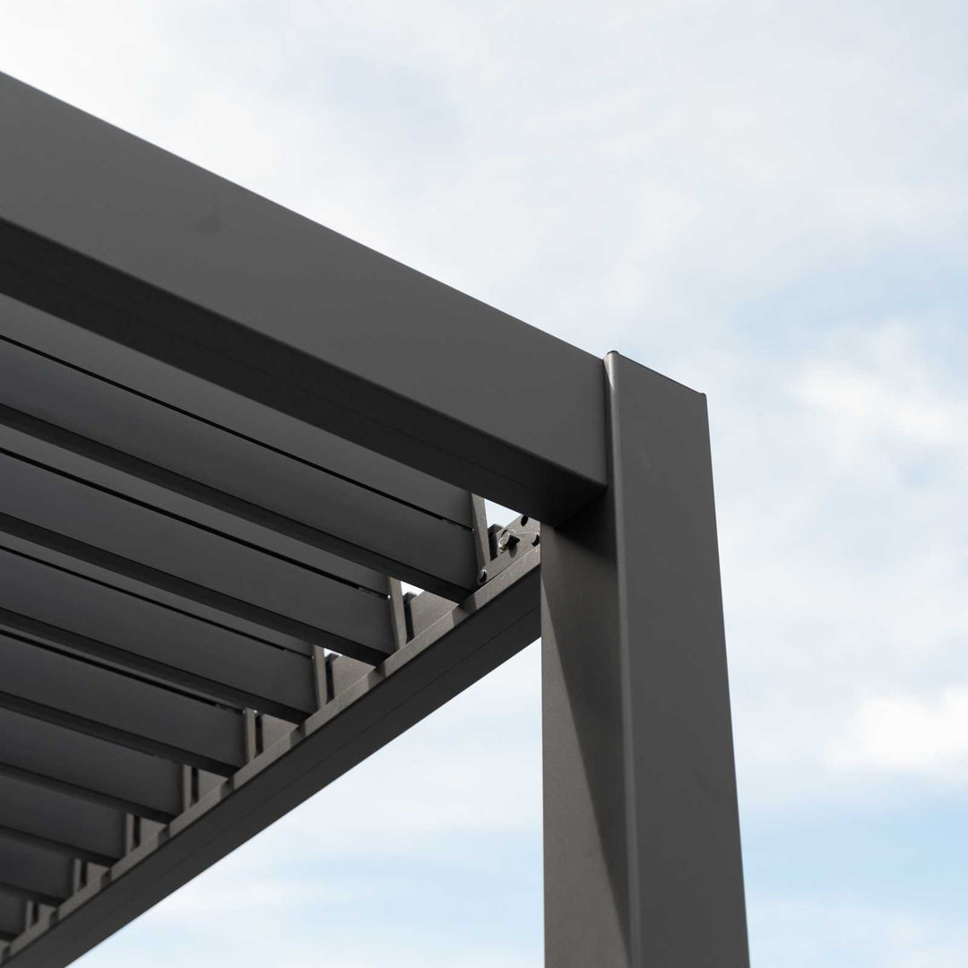 Titan Pergola Grey, corner section with louvers open showing daylight though. Blue/white sky.