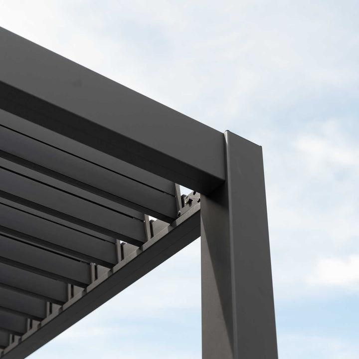Titan Pergola Grey, corner section with louvers open showing daylight though. Blue/white sky.
