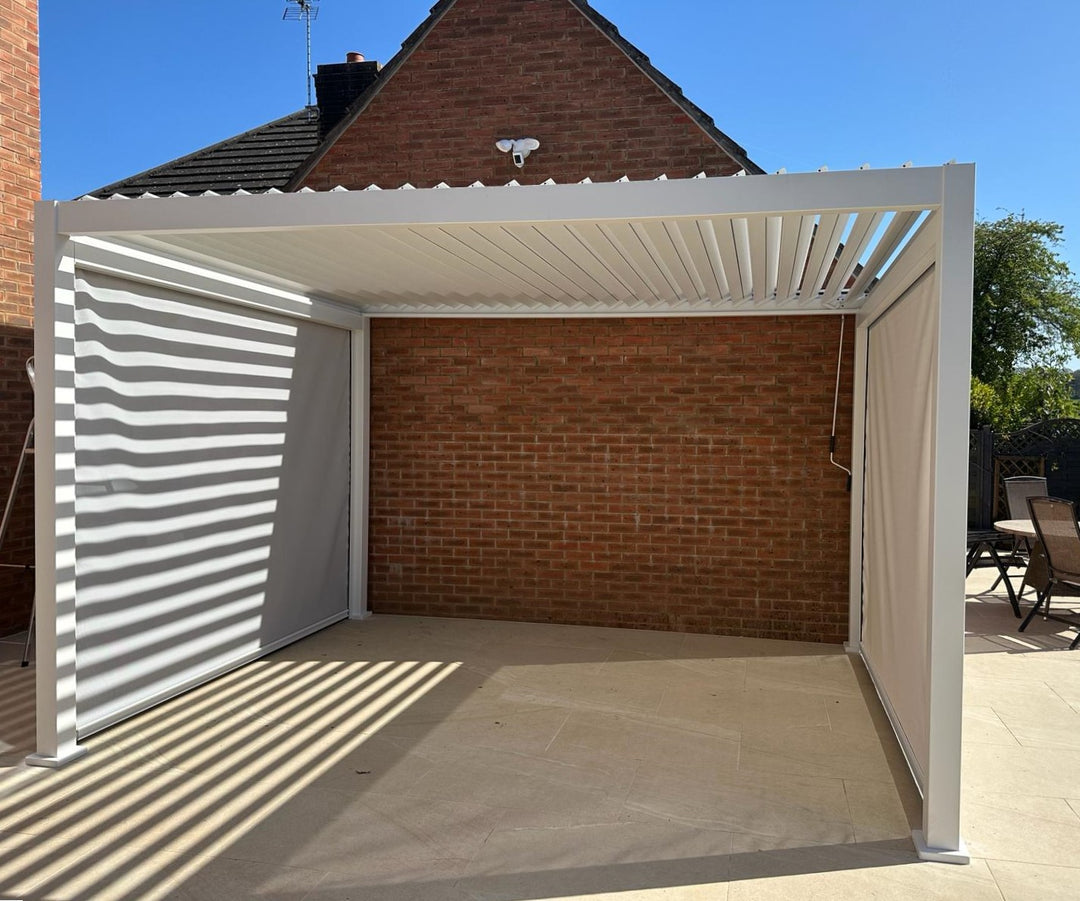 Nova Titan Pebble Grey Pergola on bright sunny day behind a modern garage with sandstone slabs underneath