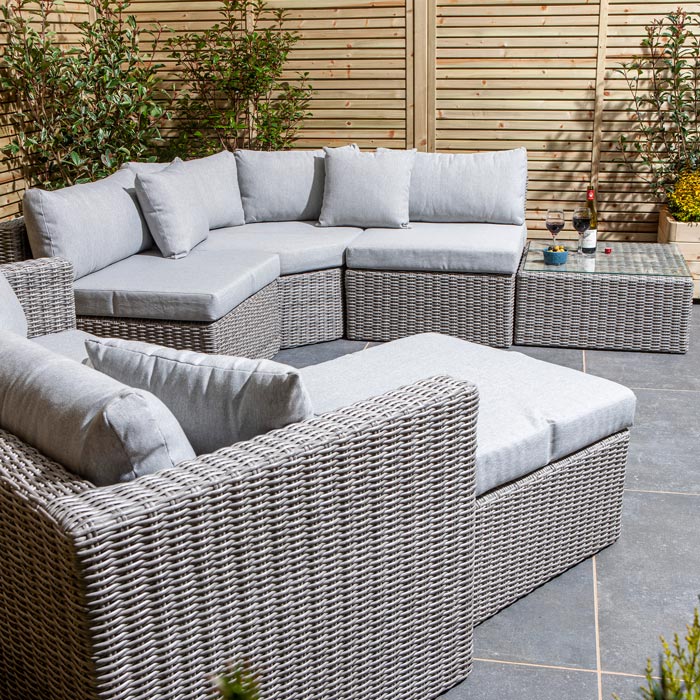 Grey outdoor sofa set with cushions on a patio area.