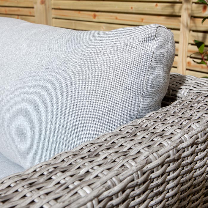 Rowlinson Marbella Multifunction Rattan Garden Furniture, with grey rattan and light grey cushions with a fence behind and bush at the back. Corner section are arm rest and cushion close up.